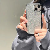 a woman holding up her phone case with a silver glitter