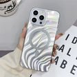 a woman holding a phone case with a silver swirl design