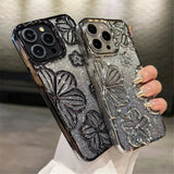 a woman holding a phone case with a silver glitter butterfly design