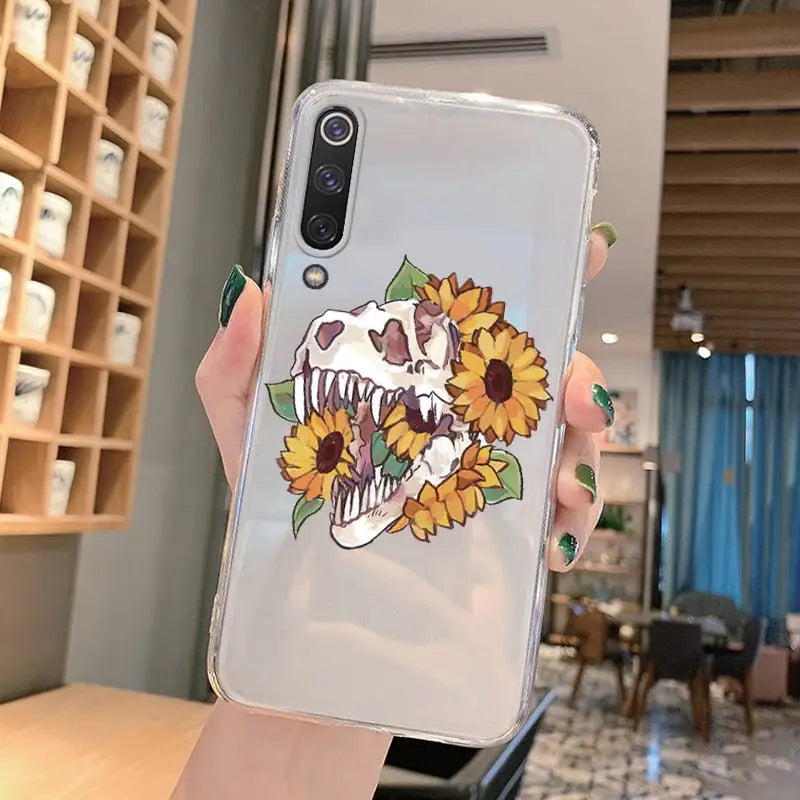 a woman holding a phone case with a skull and sunflowers