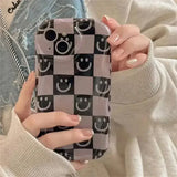 A woman holding a phone case with a smiley face pattern