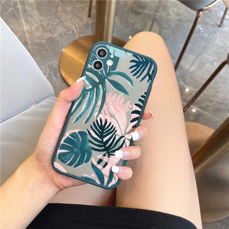 a woman holding a phone case with a tropical print