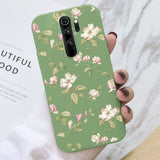 a woman holding a phone case with white flowers on it