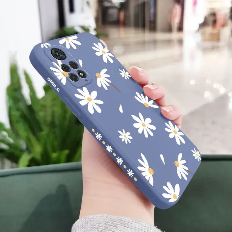 a woman holding a phone case with white flowers on it