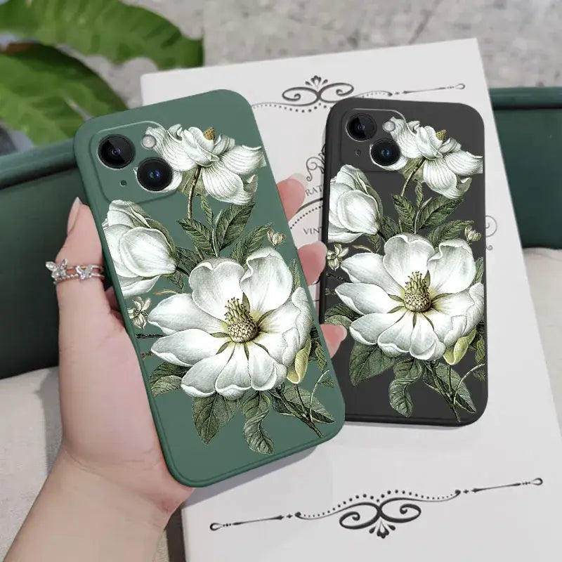 a woman holding a phone case with white flowers on it