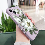 a woman holding a phone case with white flowers on it