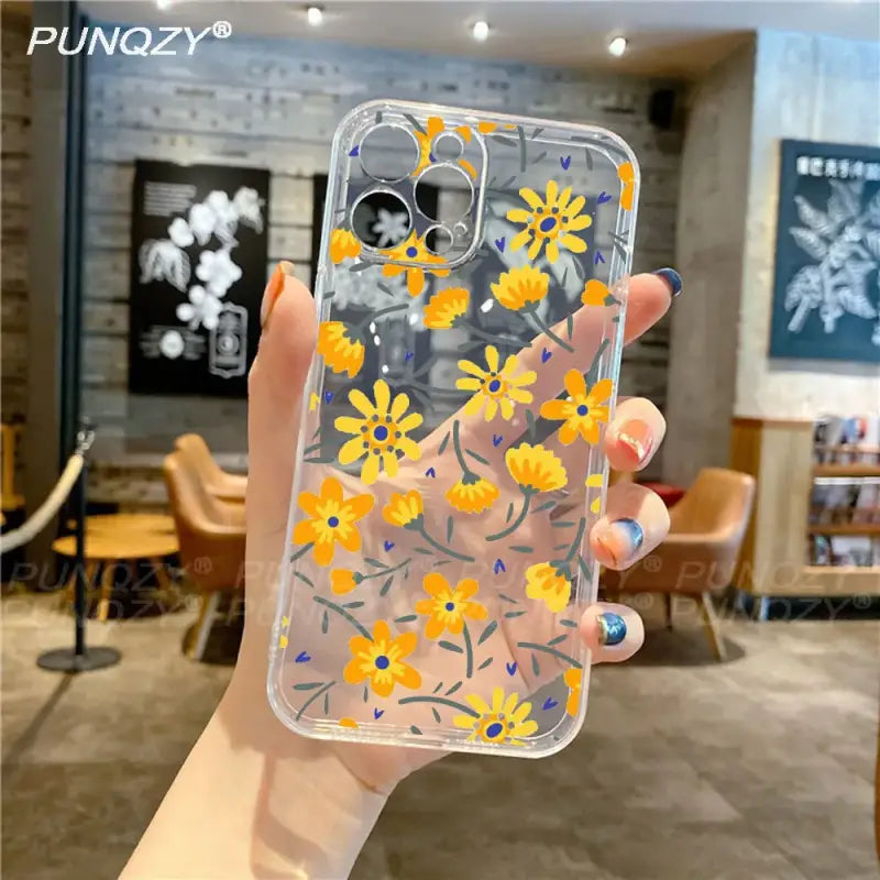 a woman holding a phone case with yellow flowers on it