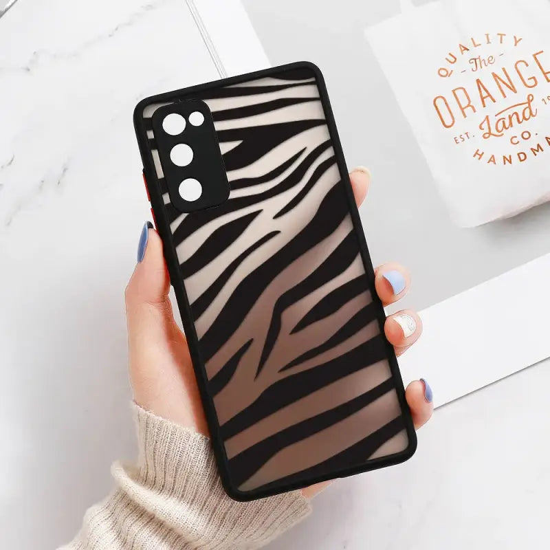 a woman holding a phone case with a zebra print
