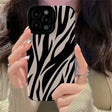 a woman holding up her phone case with zebra print