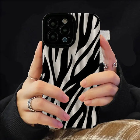 A woman holding a phone case with zebra print