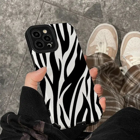 A woman holding a phone case with zebra print