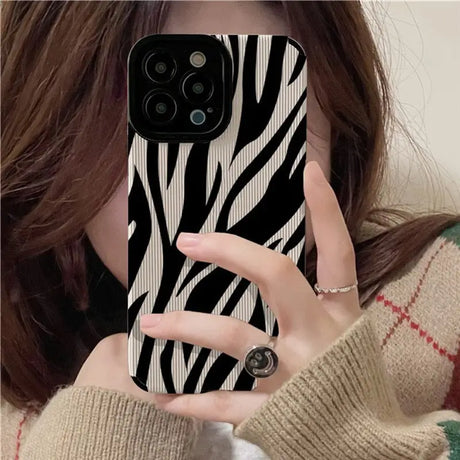 A woman holding up her phone case with zebra print