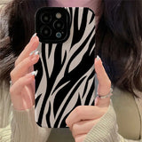 A woman holding up her phone case with zebra print