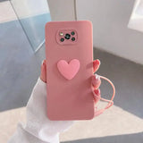 a woman holding a pink heart phone case