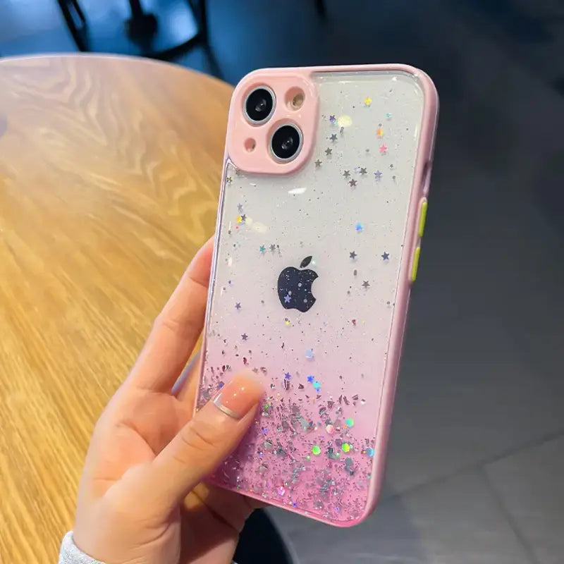a woman holding a pink iphone case with glitter and stars