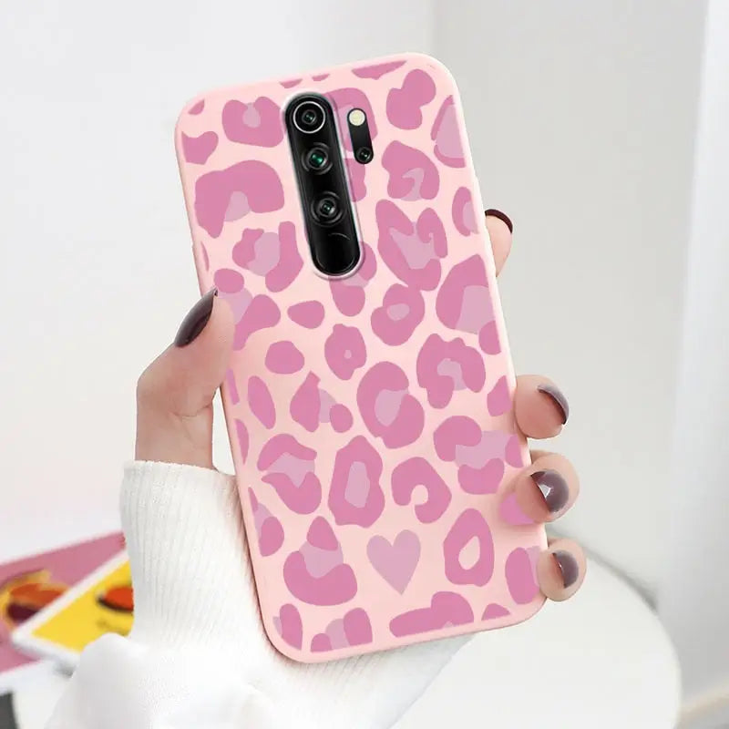 a woman holding a pink leopard print phone case