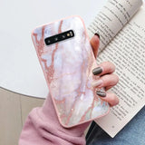 a woman holding a pink marble phone case