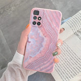a woman holding a pink marble phone case