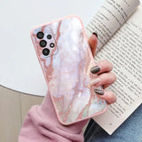 a woman holding a pink marble phone case