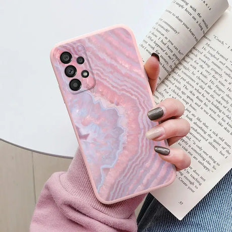 a woman holding a pink marble phone case