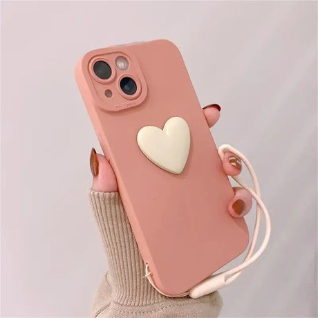 A woman holding a pink phone case with a heart