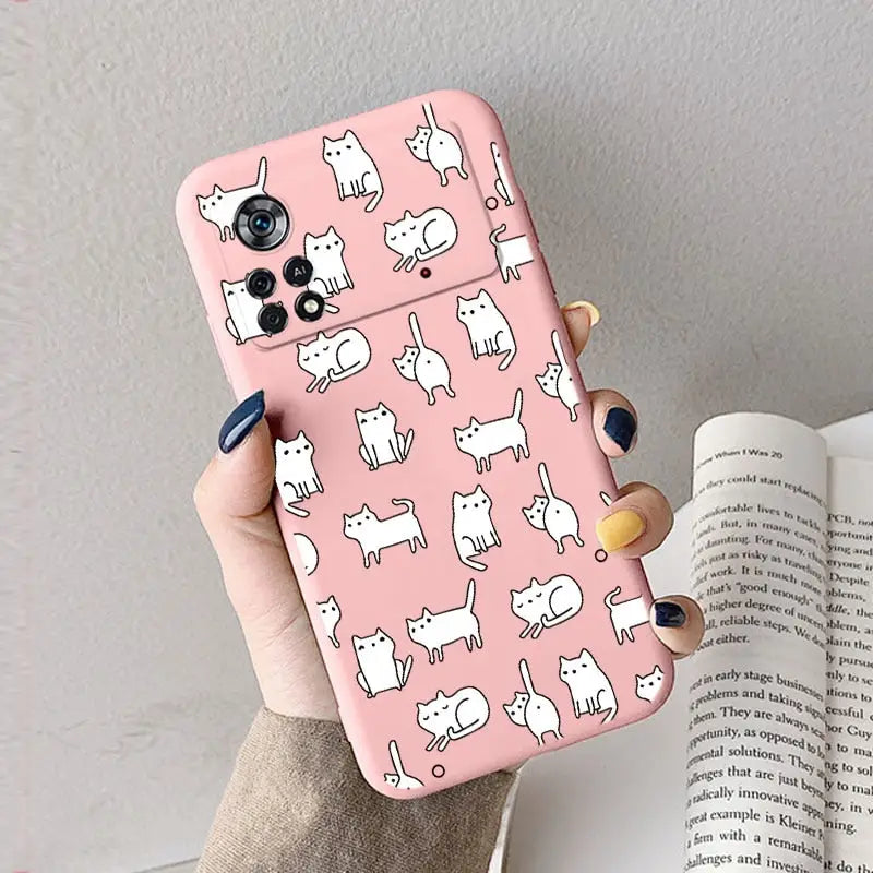 A woman holding a pink phone case with white cats on it
