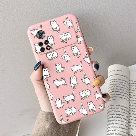 A woman holding a pink phone case with white cats on it