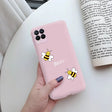 a woman holding a pink phone case with a bee on it
