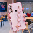 a woman holding a pink phone case with heart charms