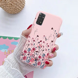 a woman holding a pink phone case with flowers on it