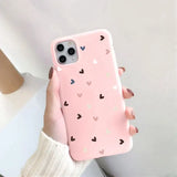 a woman holding a pink phone case with hearts on it