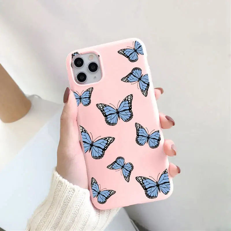 a woman holding a pink phone case with blue butterflies on it