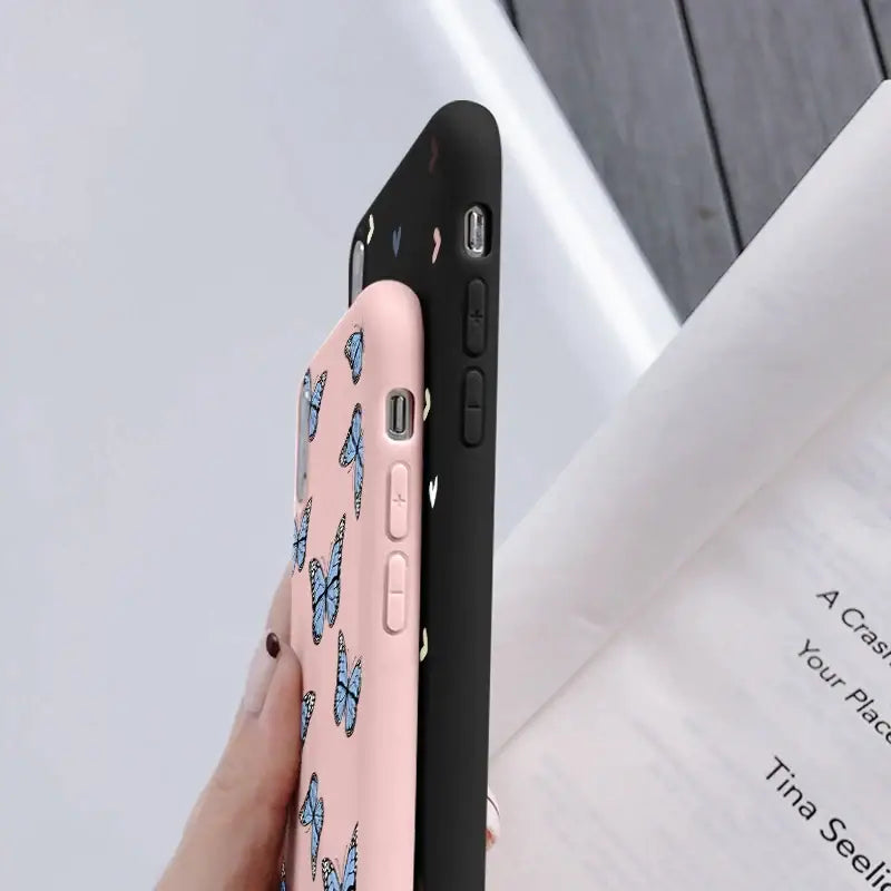 a woman holding a pink phone case with a butterfly pattern