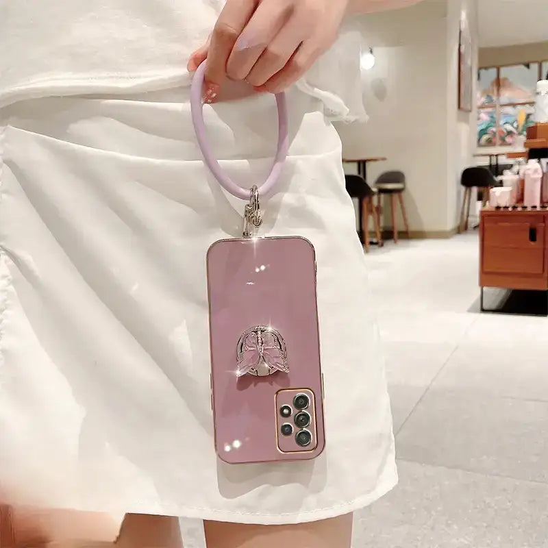A woman holding a pink phone case with a cat on it