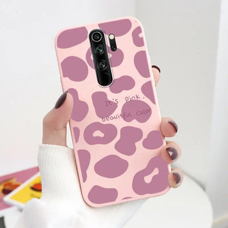 A woman holding a pink phone case with a pink leopard print