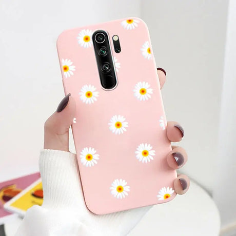 A woman holding a pink phone case with daisies on it