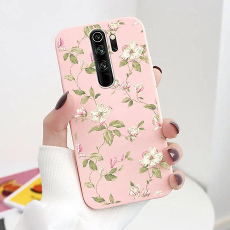 A woman holding a pink phone case with white flowers on it