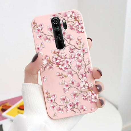 A woman holding a pink phone case with a pink flower design