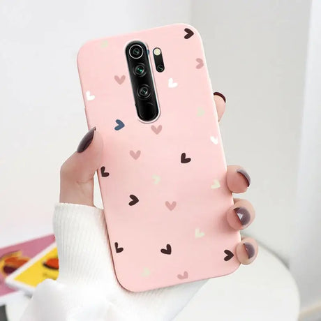 A woman holding a pink phone case with hearts on it