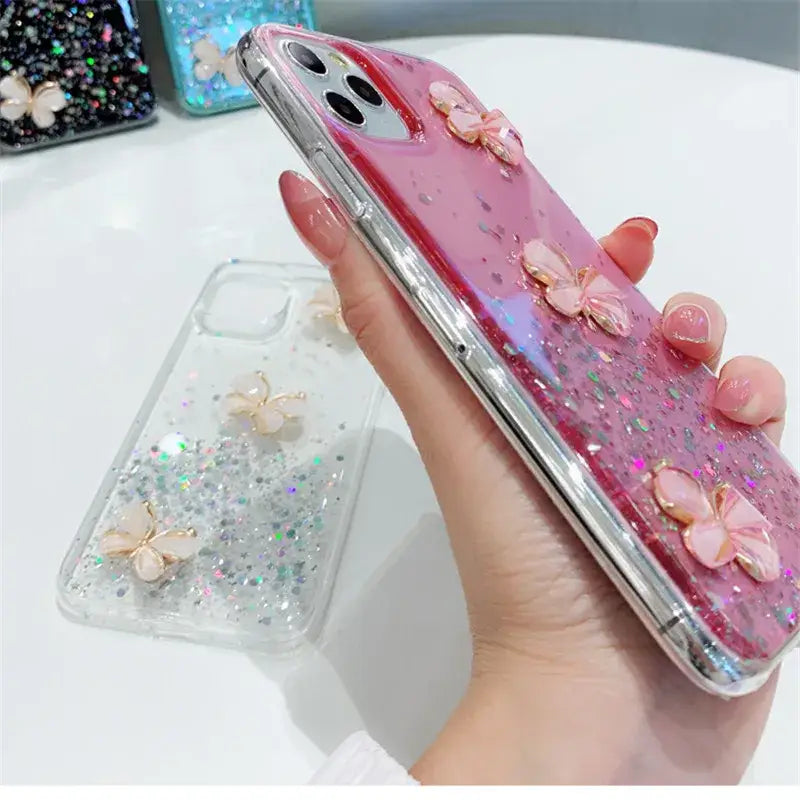 a woman holding a pink phone case with glitter and butterflies
