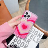 a woman holding a pink phone case with a heart on it