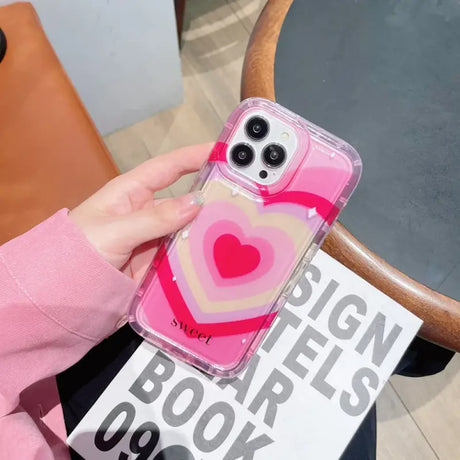 A woman holding a pink phone case with a heart on it