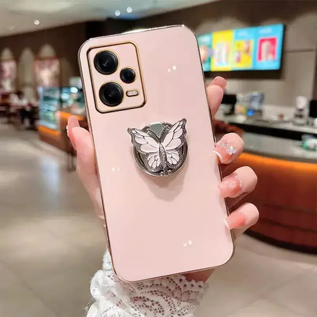 A woman holding a pink phone case with a butterfly on it