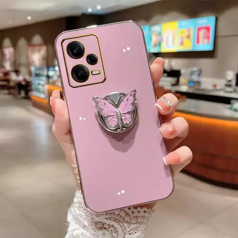 a woman holding a pink phone case with a pink butterfly on it