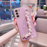 a woman holding a pink phone case with pearls and pearls