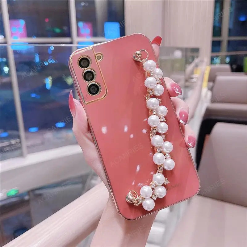 a woman holding a pink phone case with pearls and pearls