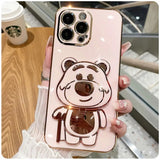 a woman holding a pink phone case with a bear on it