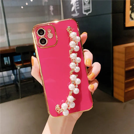 a woman holding a pink phone case with pearls and pearls