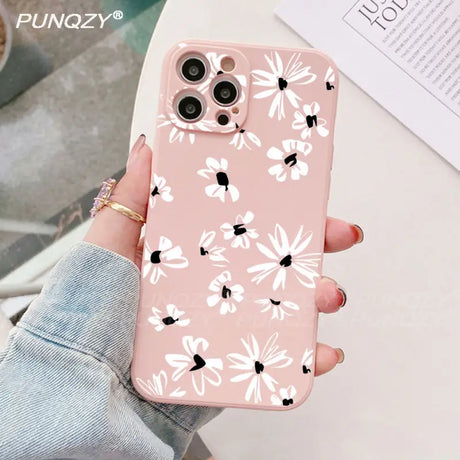 A woman holding a pink phone case with white flowers on it