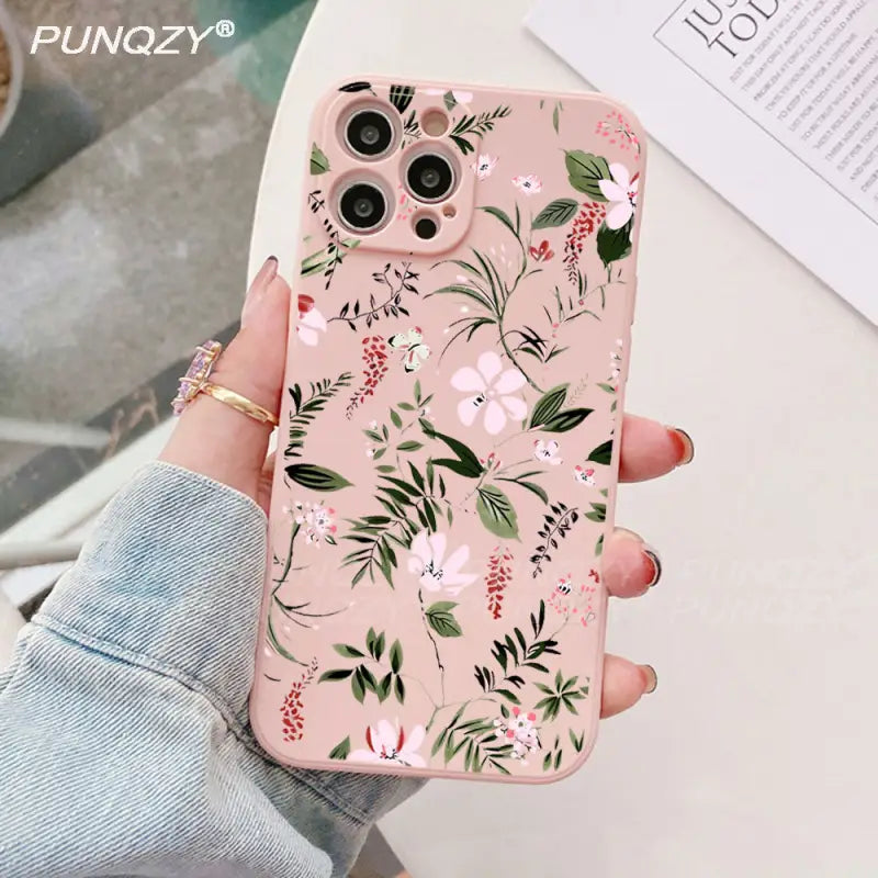 a woman holding a pink phone case with floral print